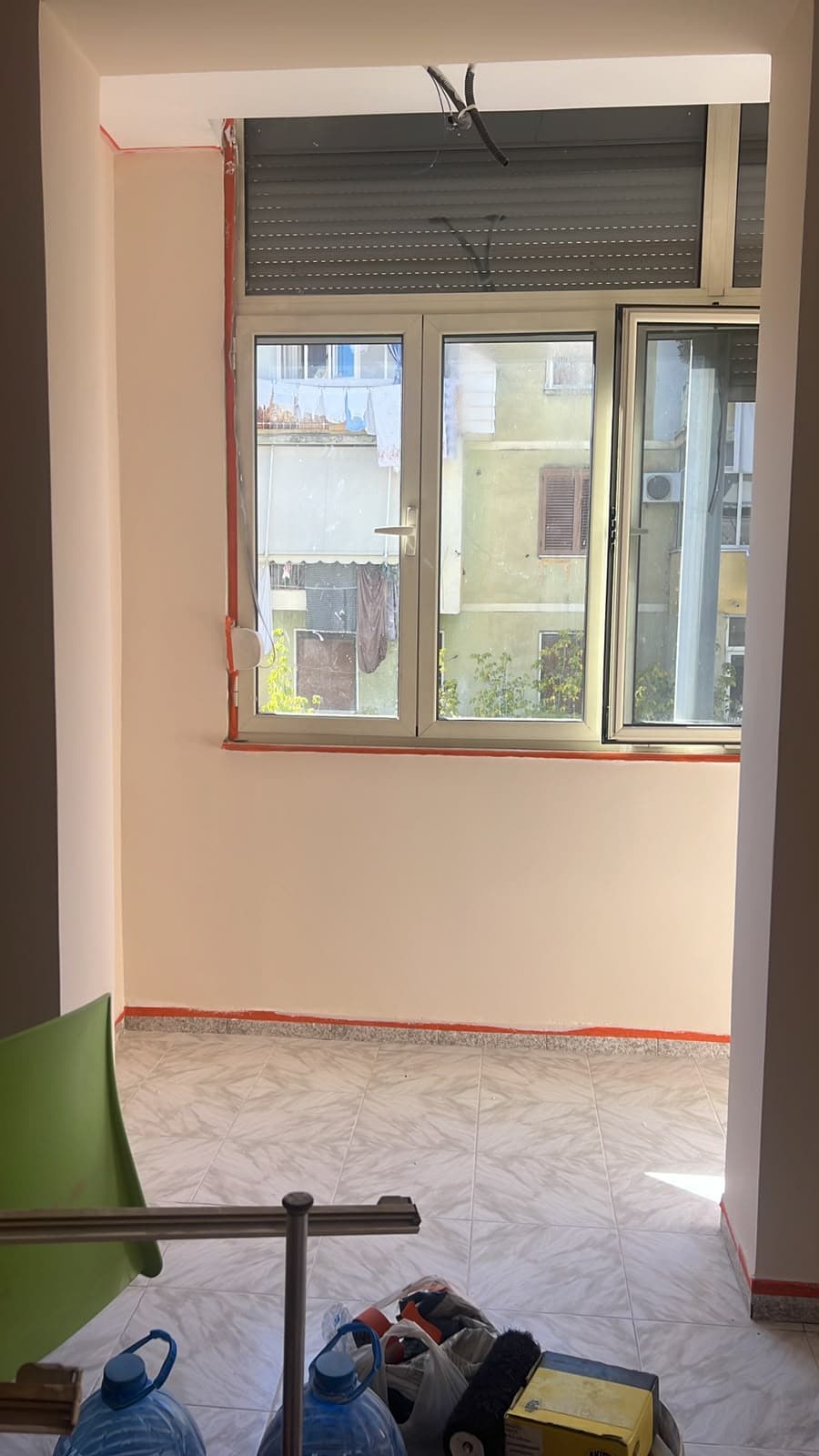 Dhomë me mure në ngjyrë krem dhe dritare të madhe pas lyerjes