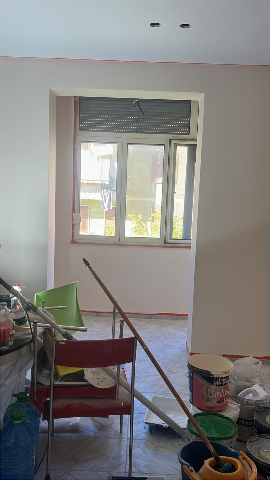 Dhomë me mure të lyera dhe dritare, gjatë pastrimit pas punimeve